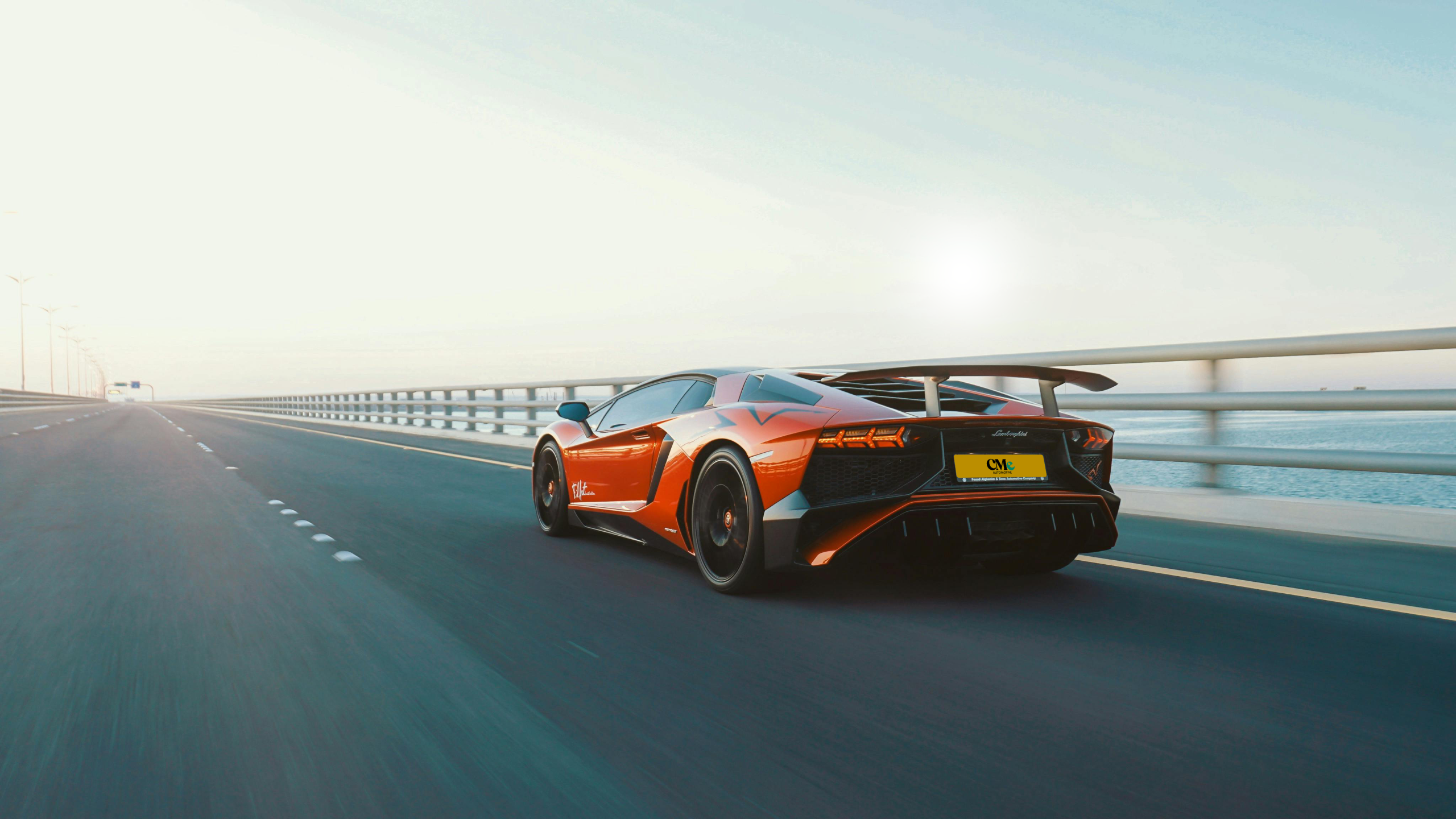 Back of the orange sports car driving forward by the sea