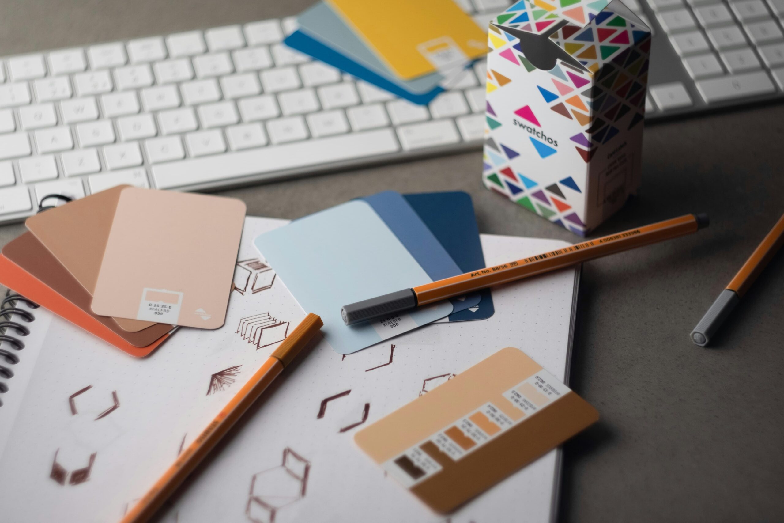 Close-up of a colorful geometric pattern box, color palette cards, and pens on a workspace.